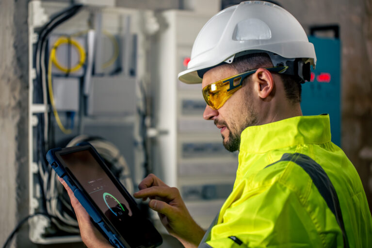 Man, an electrical technician working in a switchboard with fuses. Installation and connection of electrical equipment.